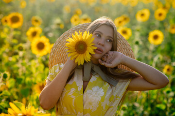 Beautiful caucasian pregnant woman walking in the summer at sunset in a field of blooming sunflower