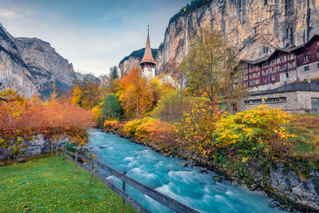 Colorful autumn view of great waterfall in Lauterbrunnen village with azure river. Marvelous outdoor scene in Swiss Alps, Bernese Oberland in the canton of Bern, Switzerland.