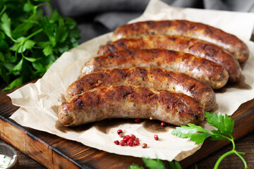 Fried sausages. Grilled sausages with spices on a wooden serving Board. Delicious meat sausages
