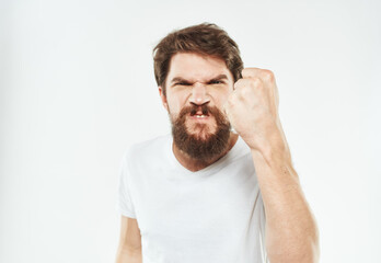 Aggressive man gestures with his hands on a light background and a thick beard