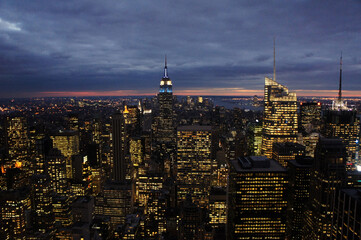 Fototapeta na wymiar New york city lights of business offices in Manhattan at dusk or dawn. Urban cityscape at twilight. Concept of overpopulated megapolis. USA/America. Home office concept during coronavirus. 