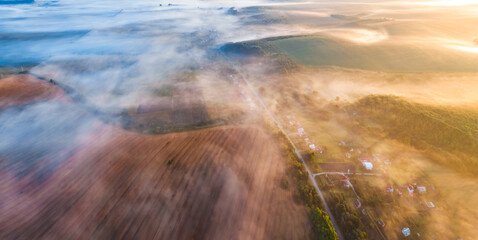 Misty summer sunrise on the countryside. Fantastic morning view from flying drone of village and plowed field, Ternopil region, Ukraine, Europe. Traveling concept background..