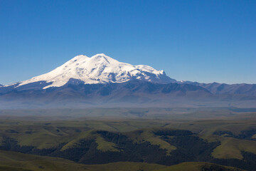 An excellent view from the plateau to the extinct volcano and the snowy peak of Mount Elbrus. Below is a green gorge