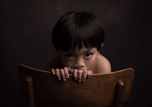 Asian Boy Looking Across Back Of Chair