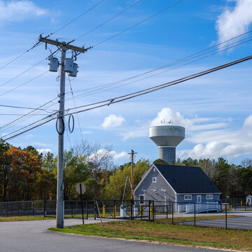 Electrical pole and cables with water tower and clouds on the backgrounds