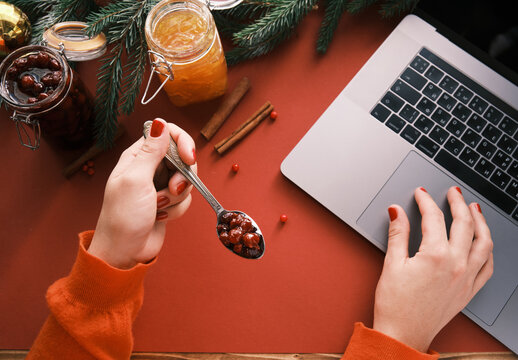 Closeup of a women hands eating bery jam and working from home on Christmas eve. Healthcare and protection
