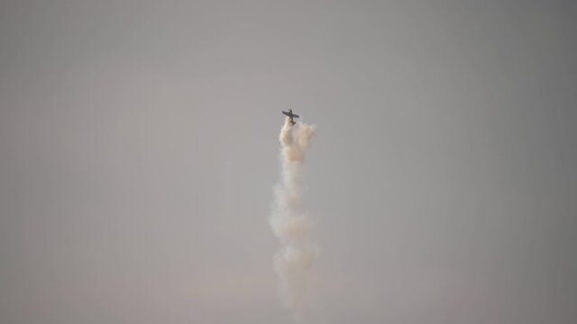 A small plane during an aerobatic simulation: plane engine failure, white smoke coming out from the engine as the plane crashes