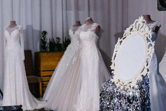 Beautiful wedding dresses, bridal dress hanging on hangers and mannequins in studio, shop. Fashion look. Interior of bridal salon. Wedding show room trendy, modern. - Image