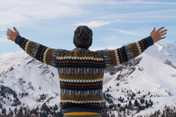 A man with his back to the ground with open arms and mountains in the background.