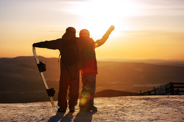 Fototapeta premium Loving couple of young people with a snowboard in deep snow.