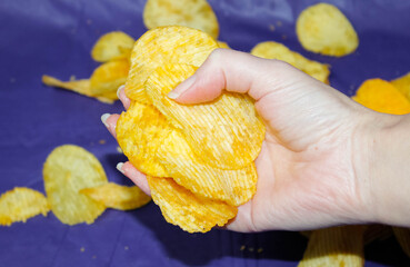 A woman's hand lifted an armful of potato chips from the dark blue tablecloth.