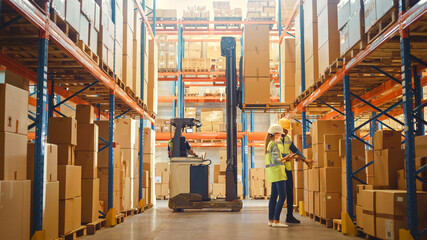 Retail Warehouse full of Shelves with Goods in Cardboard Boxes, Male and Female Supervisors Use Digital Tablet Discuss Product Delivery while Scanning Packages Forklift Working in Logistics Storehouse - obrazy, fototapety, plakaty