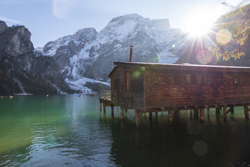 Amazing view of the, famous Braies Lake in Italy, with a wooden house in the middle. Beautiful sun flares and oblique sun rays. Bokeh effect. Emerald green water.