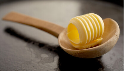 Single elegant butter curl in a wooden spoon