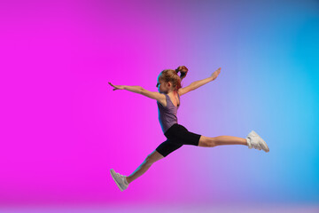 High jump. Teenage girl, professional runner, jogger in action, motion isolated on gradient pink-blue background in neon light. Concept of sport, movement, energy and dynamic, healthy lifestyle.