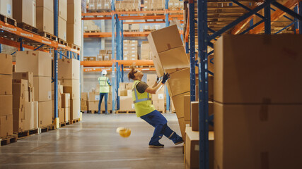 Shot of a Warehouse Worker Has Work Related Accident. He is Falling Down BeforeTrying to Pick Up Heavy Cardboard Box from the Shelf. Hard Injury at Work. - obrazy, fototapety, plakaty