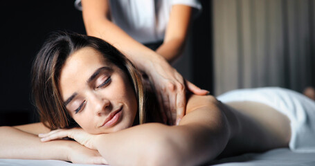 Young beautiful woman lying on massage table and enjoying massage.
