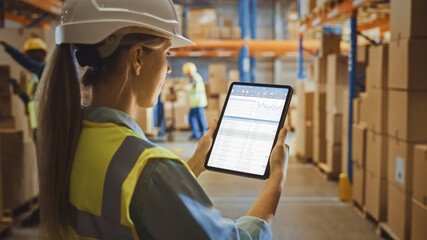 Professional Female Worker Wearing Hard Hat Uses Digital Tablet Computer with Inventory Checking...