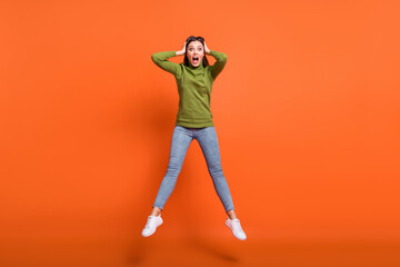 Fototapeta na wymiar Full length photo of young girl amazed shocked scared panic news jump hands touch head isolated over orange color background
