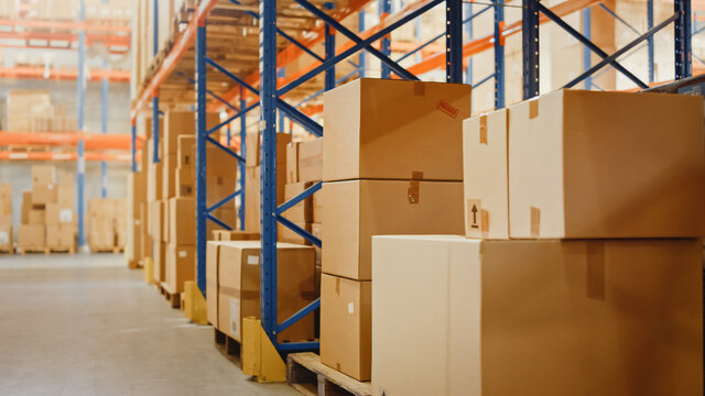 Big Retail Warehouse full of Shelves with Goods in Cardboard Boxes and Packages. Logistics, Sorting and Distribution Facility for further Product Delivery. Semi Side View