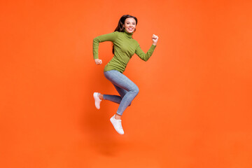 Fototapeta na wymiar Full size profile sid photo of young active crazy girl have fun enjoy run jump happy smile isolated over orange color background