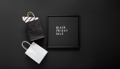 Black Friday sale text on black Letter Board with shopping paper bags on black background. Delivery mock up black and white craft paper bag package for sale.Long web banner