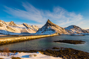 Scenic view over the bridge connecting the village Fredvang with to the Lofoten islands archipelago in Norway in golden sunlight on clear winter day