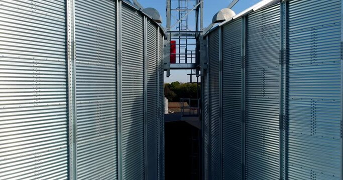 Silver grain elevators outdoors. Exterior of modern aluminum containers for storing harvest. Motion camera top down. Close-up.