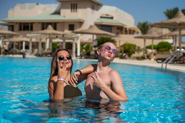 Happy family, brother and sister or a couple of teenagers or friends relaxing and have fun in swimming pool