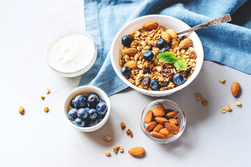 Baked granola with yogurt and blueberries on a gray table.