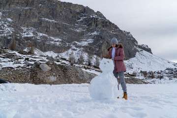 A woman making a snowman in the mountain
