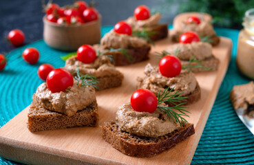 Fototapeta na wymiar Canapes with rye bread, liver pate, cherry tomatoes. Breakfast snack.