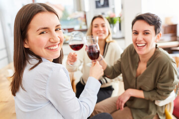 Glückliche Gruppe Frauen als Freundinnen zusammen bei Glas Rotwein
