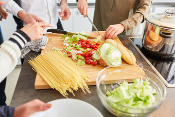 Studenten bereiten gemeinsam Salat und Pasta zu für Lunch