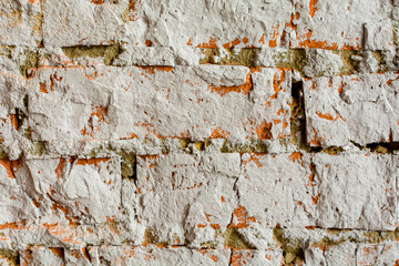 Fragment of an old brick wall covered with white plaster.