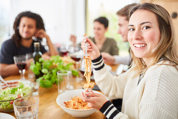 Freunde essen gemeinsam Spaghetti mit Tomatensauce in WG