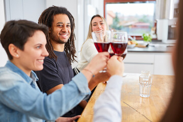 Fototapeta premium Glückliche Freunde zu Hause stoßen mit Glas Rotwein an