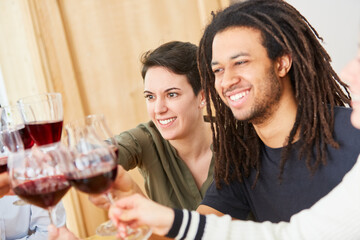 Glückliche Gruppe Freunde stößt mit Glas Rotwein an