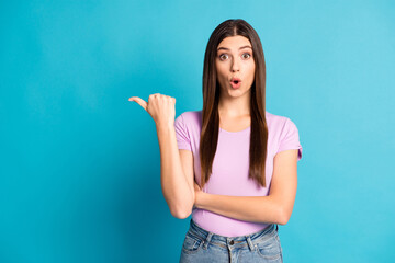 Photo of impressed student girl wear casual violet outfit jeans pointing empty space isolated blue color background