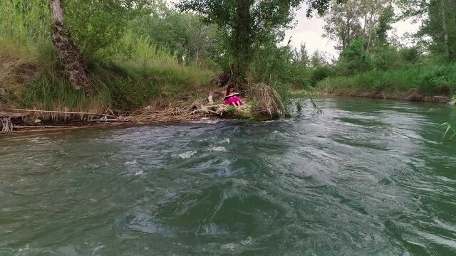 Ni&ntilde;a joven dibujando junto a un r&iacute;o y dron volando sobre aguas bravas
