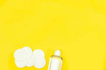 Makeup remove skin care. Tonic for face skin or makeup remover in a plastic bottle, cotton pads and wooden cotton buds on yellow background. Hygiene supplies, beauty tools and skin