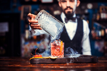 Focused bartender demonstrates the process of making a cocktail  