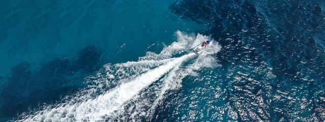 Aerial drone ultra wide photo of jet ski watercraft cruising in high speed in deep blue open ocean...