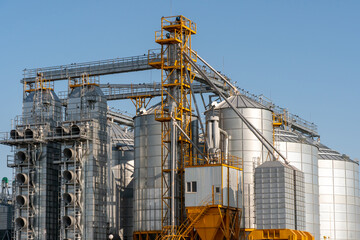 Fototapeta na wymiar silver silos on agro manufacturing plant for processing drying cleaning and storage of agricultural products, flour, cereals and grain. Large iron barrels of grain. Granary elevator