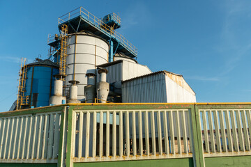 silver silos on agro manufacturing plant for processing drying cleaning and storage of agricultural products, flour, cereals and grain. Large iron barrels of grain. Granary elevator