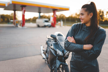 Biker girl in a leather suit near her motorcycle