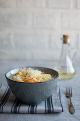 Gray bowl with sauerkraut on a gray linen napkin. Image with copy space, vertical orientation, side view.