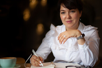 Young woman in business white blouse writing notes