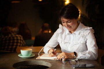Young woman in business white blouse writing notes
