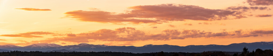 Fototapeta na wymiar Styrian Lavanttaler Alps covered with snow in orange light of sunset. Background or banner